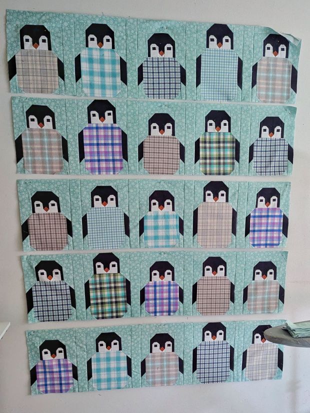 Penguin Party Christmas quilt in progress, made with plaid flannels in a cool-toned color palette with aqua snowflake background