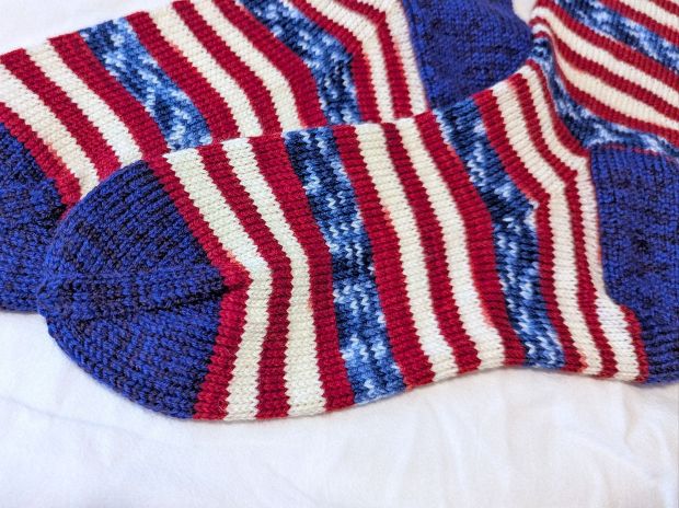 Handknit socks made with self-striping American Flag yarn from The Painted Tiger with contrasting heels knit with Cascade Yarns Heritage sock yarn in royal blue.
