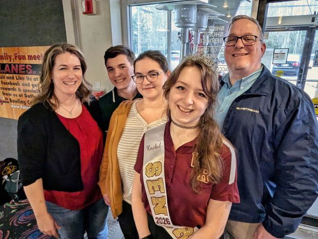 A senior high school girl wearing a personalized senior sash with gold and maroon letters