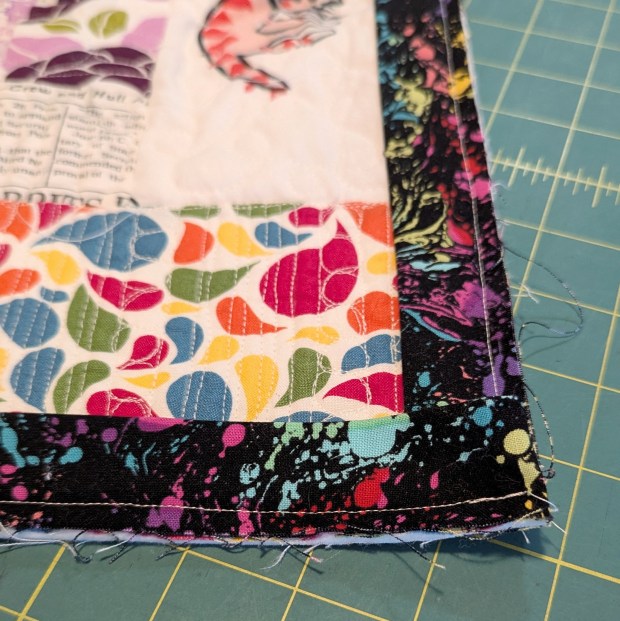 Rainbow Coin Strip Scrap Quilt with black venom binding